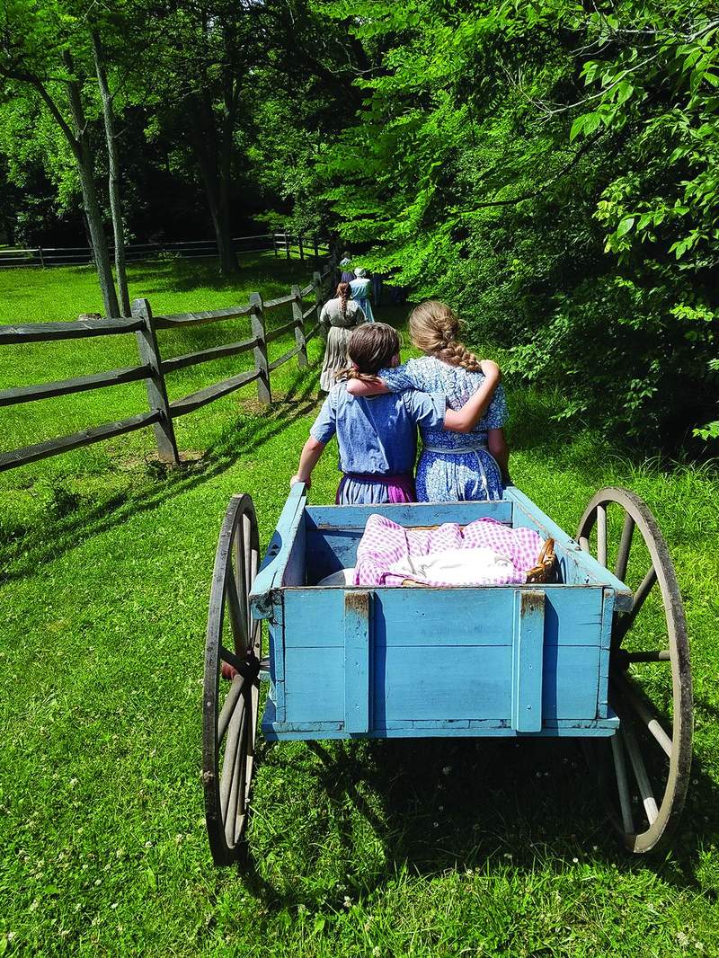 Interpreters in period dress with a farm wagon